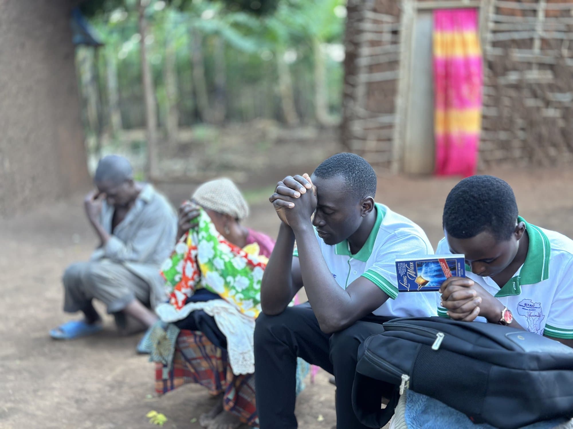 STAC team members praying with a family in Kyangwali Refugee Settlement